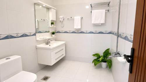 a white bathroom with a sink and a shower at Royal Palm Villa in Rawalpindi