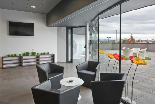 a lobby with chairs and a table and a tv at Sercotel Hola Tafalla in Tafalla