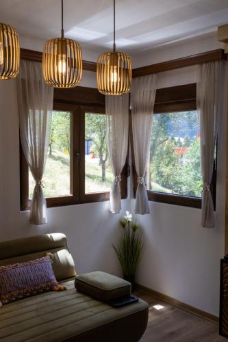 a living room with a couch and two windows at Apartman Smaragd Lux in Plužine