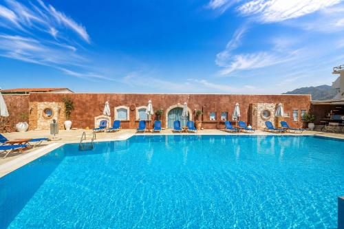 a large swimming pool with blue chairs in front of a building at Golden Bay Apartments-Garden Haven in Malia