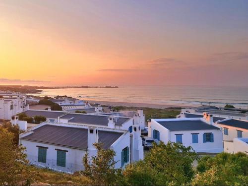 a group of white houses on the beach at sunset at Skye in Paternoster