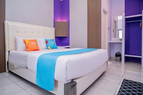 a bedroom with a large bed with colorful pillows at SANS Vibes Violeta Inn Jambi in Jambi