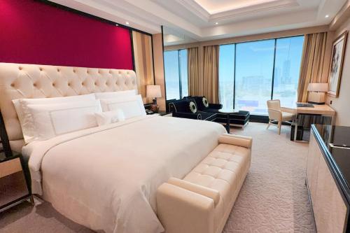 a bedroom with a large white bed with a red wall at The Trans Luxury Hotel Surabaya in Surabaya