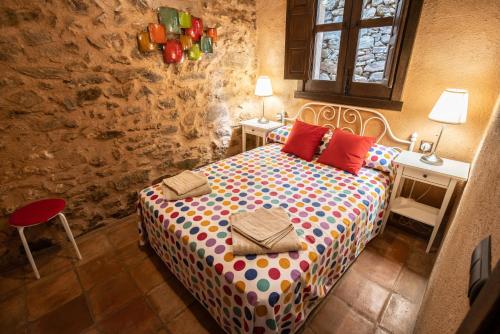 a bedroom with a bed with colorful sheets and two tables at Sierra de Gata EL CORRAL DE LA HIGUERA in Torre de Don Miguel