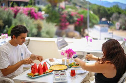 Ein Mann und eine Frau sitzen an einem Tisch und essen Essen in der Unterkunft Sea Garden Kaş Hotel in Kaş