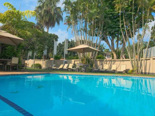 a large blue swimming pool with trees and umbrellas at Lakeview Cabanas - Unit 11 in St Lucia