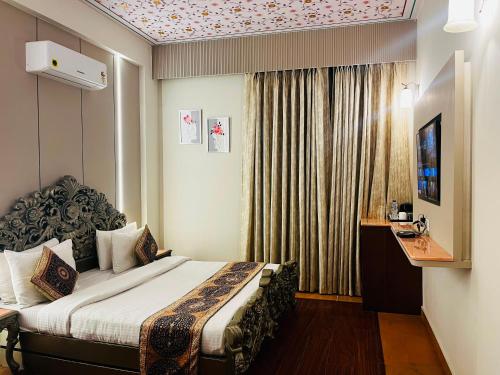 a hotel room with a bed and a window at HotelMaple Ridge in Tājganj