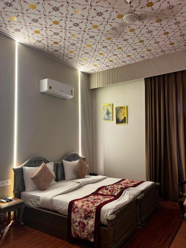 a bedroom with a bed with a flowery ceiling at HotelMaple Ridge in Tājganj
