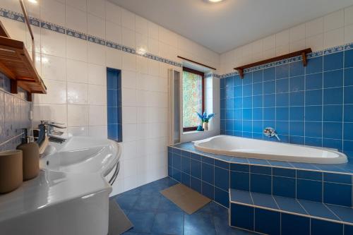 a blue tiled bathroom with a tub and a sink at Vila Fénix in Kutná Hora