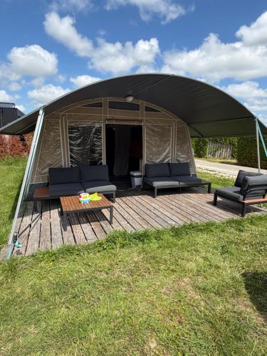 a tent with couches and a table in a field at Glamping in Style in Dronrijp