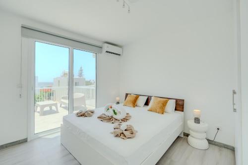 a white bedroom with a white bed and a balcony at Sandy Beach Complex in Perivolia
