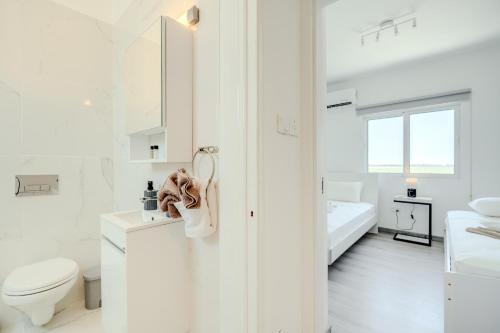 a white bathroom with a toilet and a sink at Sandy Beach Complex in Perivolia