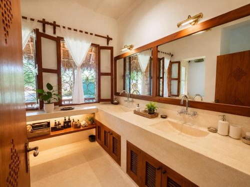 a bathroom with two sinks and a large mirror at Saffron Garden Malindi in Malindi