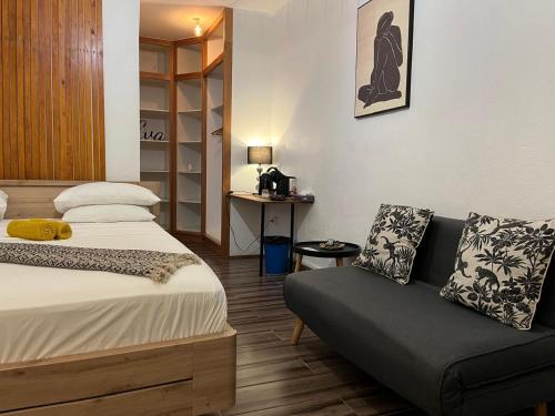 a bedroom with a bed and a couch and a table at Moya Résidence by MD in Dzaoudzi