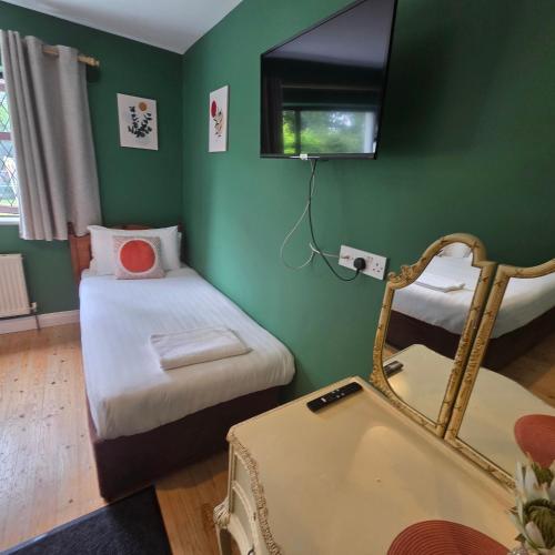 a green room with two beds and a mirror at Ely House B&B in Shannonbridge