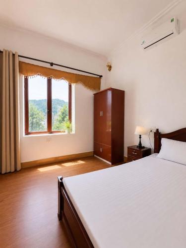a bedroom with a large bed and a window at Nhà nghỉ Hoa Ngàn Tam Đảo in Tam Ðảo