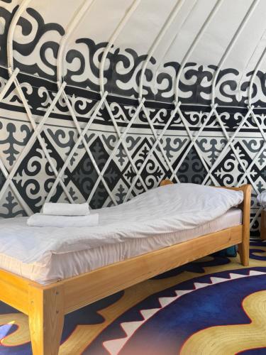 a bed in a room with a black and white wall at Sabi Guest House in Bokonbayevo