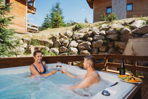 a man and a woman sitting in a hot tub at Chalets Jasná Collection - Apartments in Belá