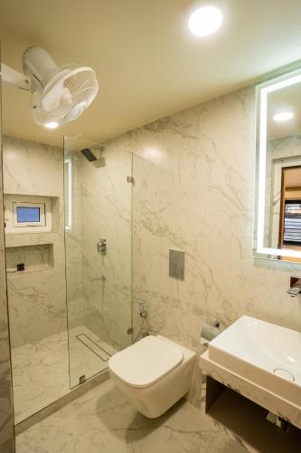 a bathroom with a shower and a toilet and a sink at Fit Haus - A Boutique Hotel in Kolkata