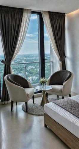 a hotel room with two chairs and a bed and a window at The Vista 1BR by Winchester in Mall of Islamabad F-7 Margalla & City Views in Islamabad