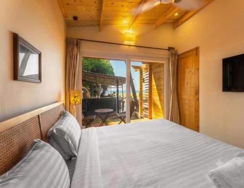 a bedroom with a bed and a large window at Morii by the sea - Morjim Beach in Morjim