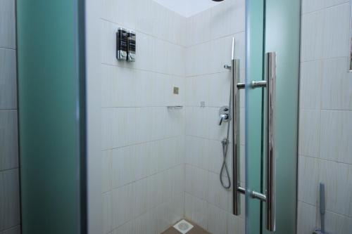 a shower with a glass door in a bathroom at 3 bedrooms Entebbe Lake-House with Pool,Private Beach, Kids Park and AC in Kagolomolo