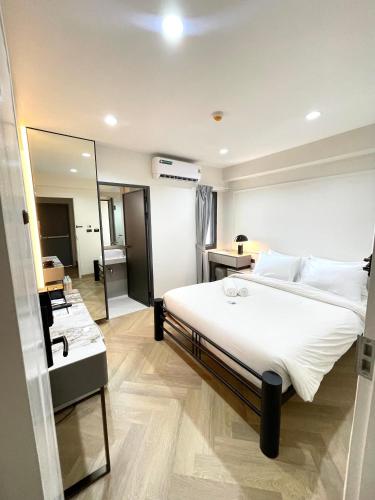 a bedroom with a large white bed and a mirror at RESET at DMK Hotel in Don Muang Airport