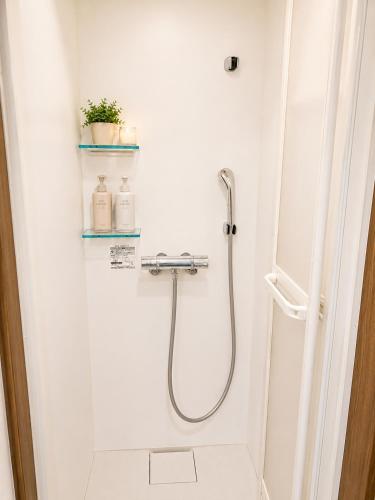 a shower in a white bathroom with a glass door at Heart Warmer in Myoko