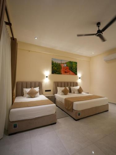 a bedroom with two beds and a painting on the wall at Lumora Fresh Wave Arugambay in Arugam Bay