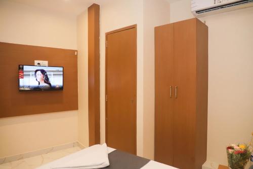 ein Zimmer mit einem Fernseher und einem braunen Schrank in der Unterkunft Hotel Pramila in Mumbai
