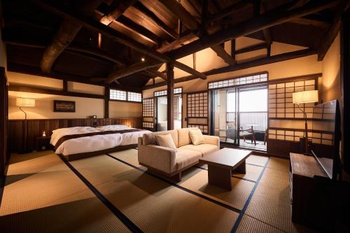 a large bedroom with a bed and a couch at いっぺ The Sake Ryokan in Kyonan