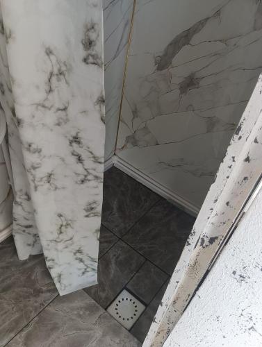 a bathroom with a white marble wall and a shower at ИНХаус Долинка in Cholpon-Ata