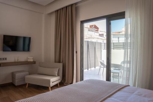 a bedroom with a bed and a chair and a balcony at LUMINA Luxury Suites in Missolonghi