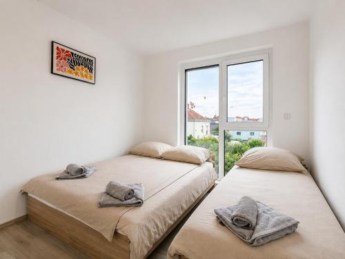 two beds in a white room with a window at TO-HAD, Modern Apartments next to U-bahn with free Wifi in Vienna