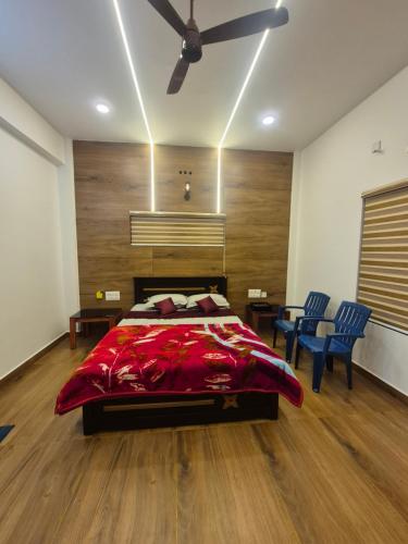 a bedroom with a bed and two blue chairs at Vrindavan Villa Homestay in Cherambane