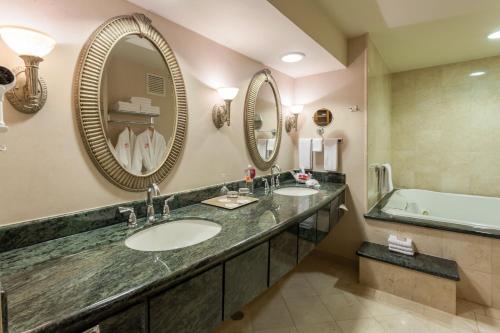 a bathroom with two sinks and a tub and mirrors at Crowne Plaza Torreon by IHG in Torreón