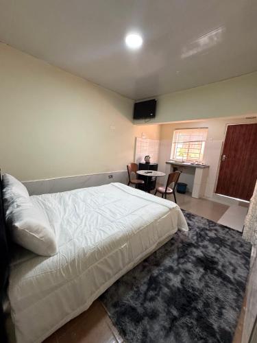 a bedroom with a bed and a table with chairs at ELISAM Cabin 2 in Kitwe