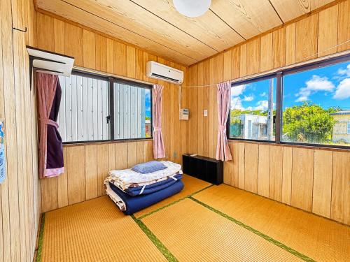 a room with a bed in a room with windows at 民宿池田屋 in Taketomi