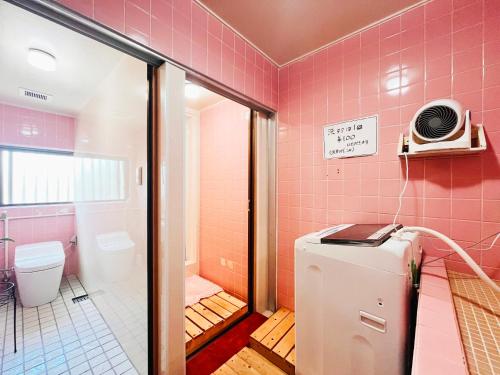 a pink bathroom with a toilet and a refrigerator at 民宿池田屋 in Taketomi