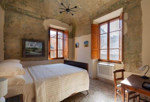 a bedroom with a bed and a table and windows at Il Casone di Rigomagno in Rigomagno
