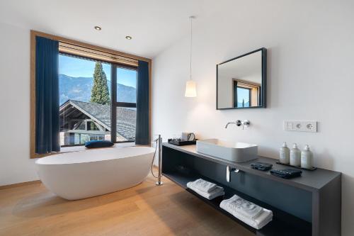 a bathroom with a tub and a sink and a window at Wine Lodge Pratenberg in Merano