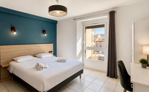 a bedroom with a bed with a blue wall and a window at Apparthotel de Langogne in Langogne