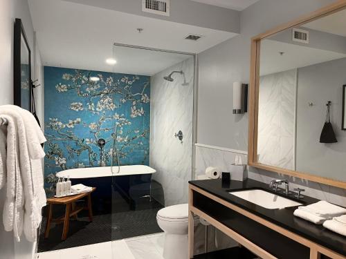 a bathroom with a toilet and a sink and a tub at Kimpton Schofield Hotel by IHG in Cleveland