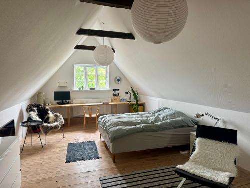 a bedroom with a bed and a desk in a attic at Fred & Lyst in Stenløse