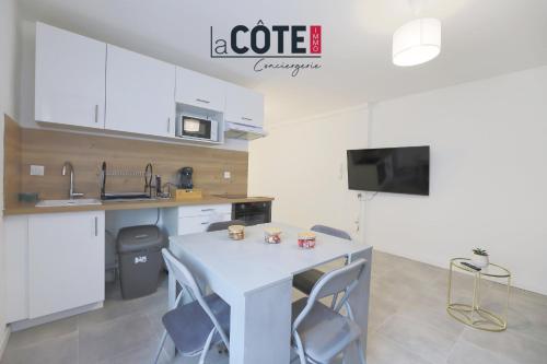 a white kitchen with a table and chairs and a tv at Duplex Villebois in Port-de-Bouc