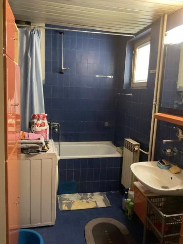 a blue tiled bathroom with a tub and a sink at City centar apartman in Zaječar