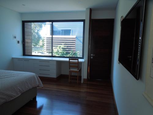 a bedroom with a window with a chair and a desk at Beach Side Garden Apartment in Perth