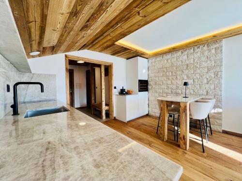 a living room with a table and a stone wall at Attique de la Moubra 4 in Crans-Montana