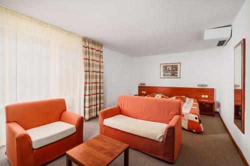 ein Wohnzimmer mit zwei Stühlen und einem Bett in der Unterkunft Hotel Fenix - All Inclusive in Sonnenstrand