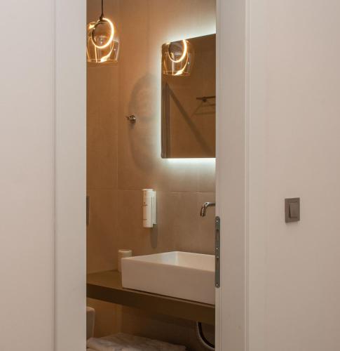 a bathroom with a white sink and a mirror at LUMINA Luxury Suites in Missolonghi